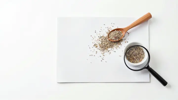 Colher de sal grosso e tigela de tempero misturado ao lado de uma lupa sobre um cartão em branco